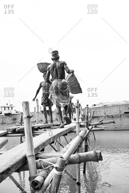 May 14, 2013: Barisal, Bangladesh; Low-income laborers are carrying coal unloaded from a cargo ship on the head at a river bank in rural Bangladesh; Black and white photography