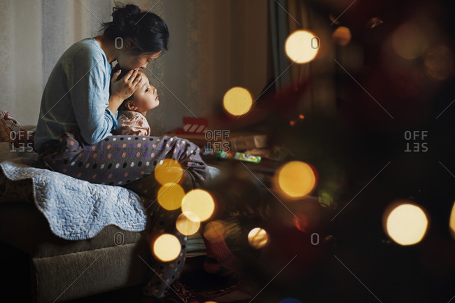Mother kissing her daughter at home decorated for Christmas holiday