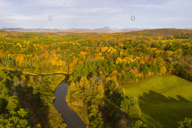 Aerial view over a forest and Lewis Creek in autumn in Charlotte, Vermont