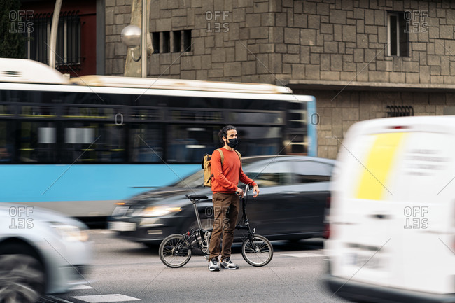 man wearing face mask riding a bike in the city.