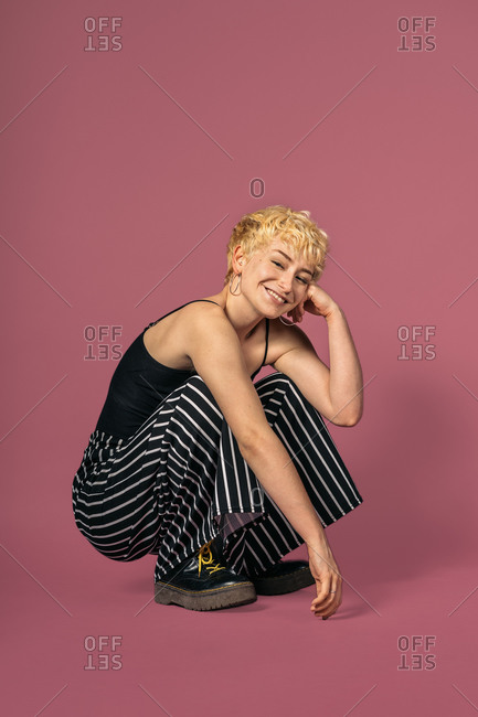 smiley girl posing in studio and looking at camera over pink background.