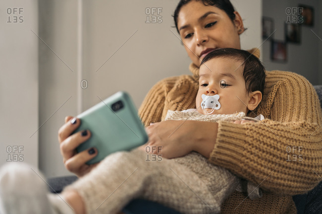 happy mother and her baby watching cartoons in the phone at home.