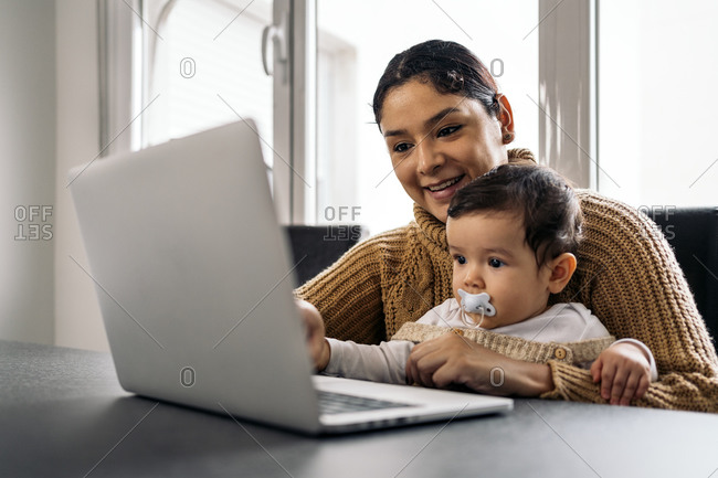 Stock photo of happy mother and her baby watching cartoons in the computer at home.