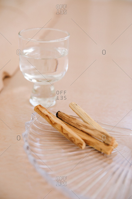 Charred wooden sticks on glass dish beside a glass cup