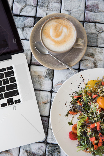 Breakfast served with a cappuccino on an outdoor table beside a laptop