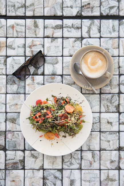 Breakfast served with a cappuccino on an outdoor table beside sunglasses