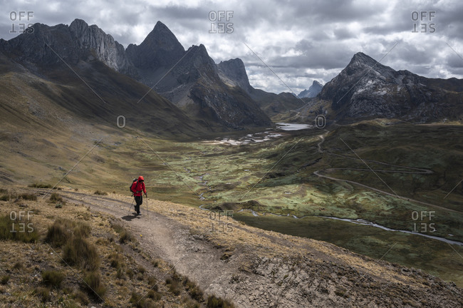 One person with poles hiking along a trail at the huayhuash circuit