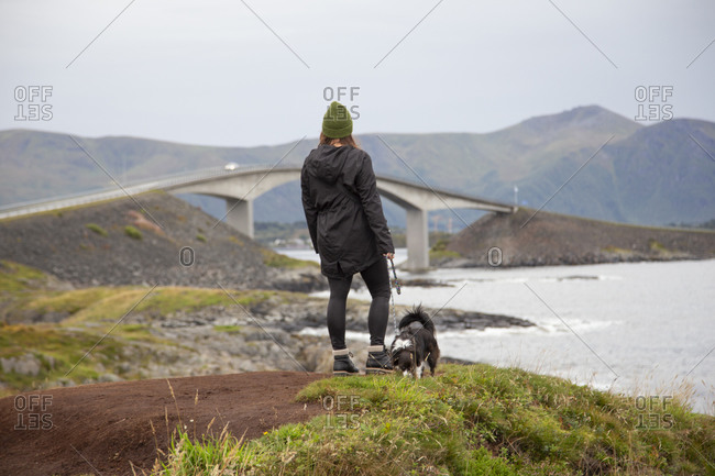 A person and their dog looking at the ocean in norway
