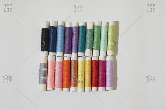 Group of multicolor reel of sewing thread on white background.