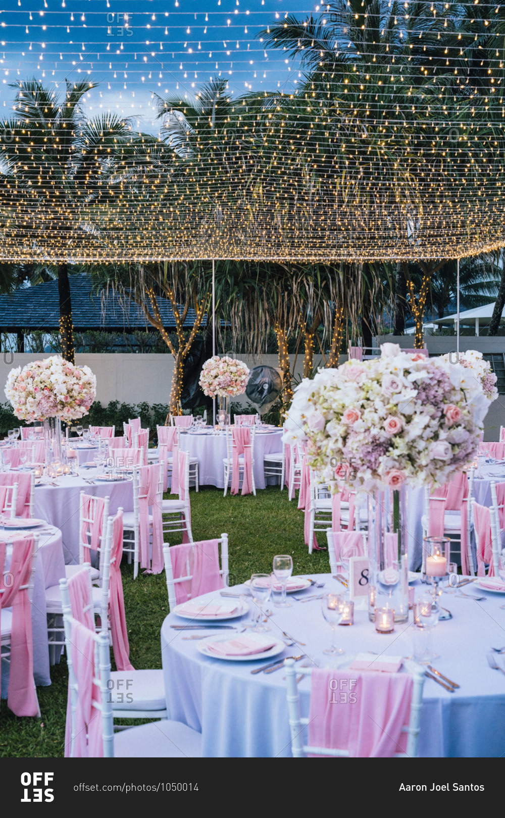 Tables at an outdoor wedding reception at dusk with fairy lights