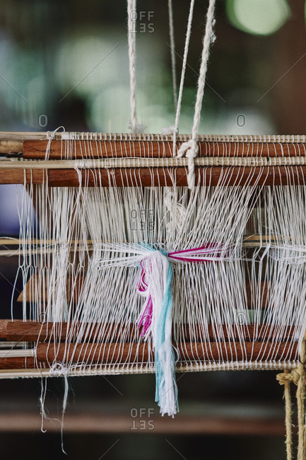 Colorful silks strings being made into fabric for weaving scarves and blankets on a traditional loom