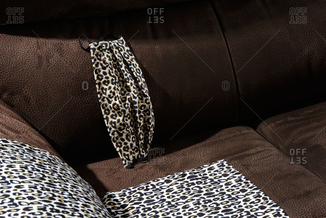 A face mask made with a leopard-patterned fabric, on a sofa