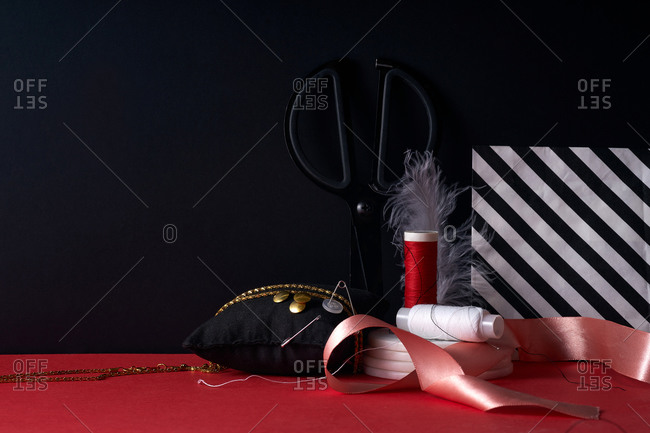 Still life of sewing items on red and black background with copy space