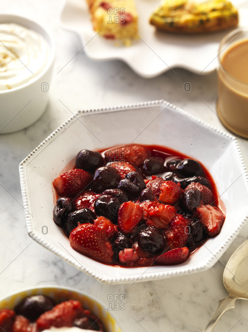 A breakfast table set with roasted summer fruit, yogurt and coffee.