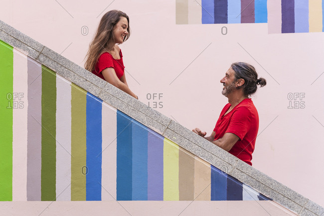 Father and daughter standing on colorful staircase during sunny day