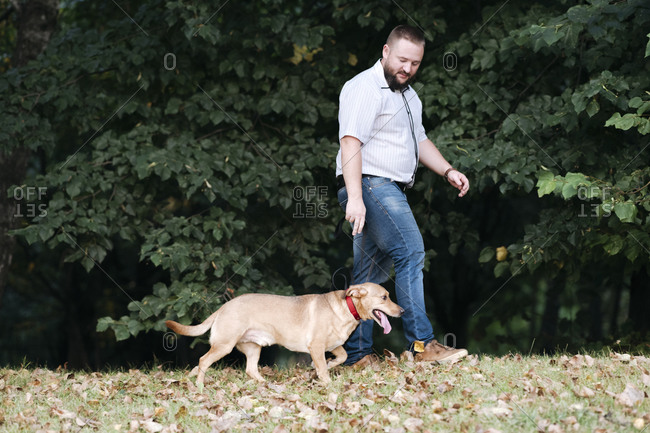 Man spending leisure time while walking with dog in park