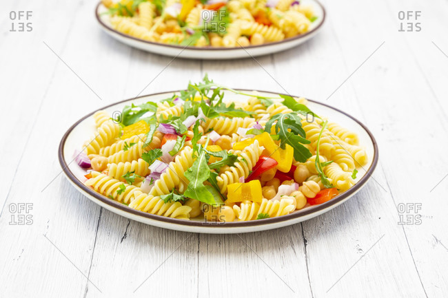 Plate of vegetarian pasta salad with chick-peas- bell pepper- arugula- onion- parsley and basil