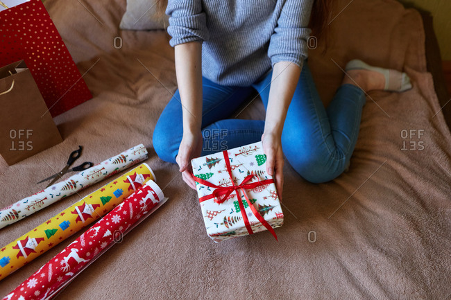 Top view of a woman decorating Christmas gifts in wrapping paper and ribbon at home