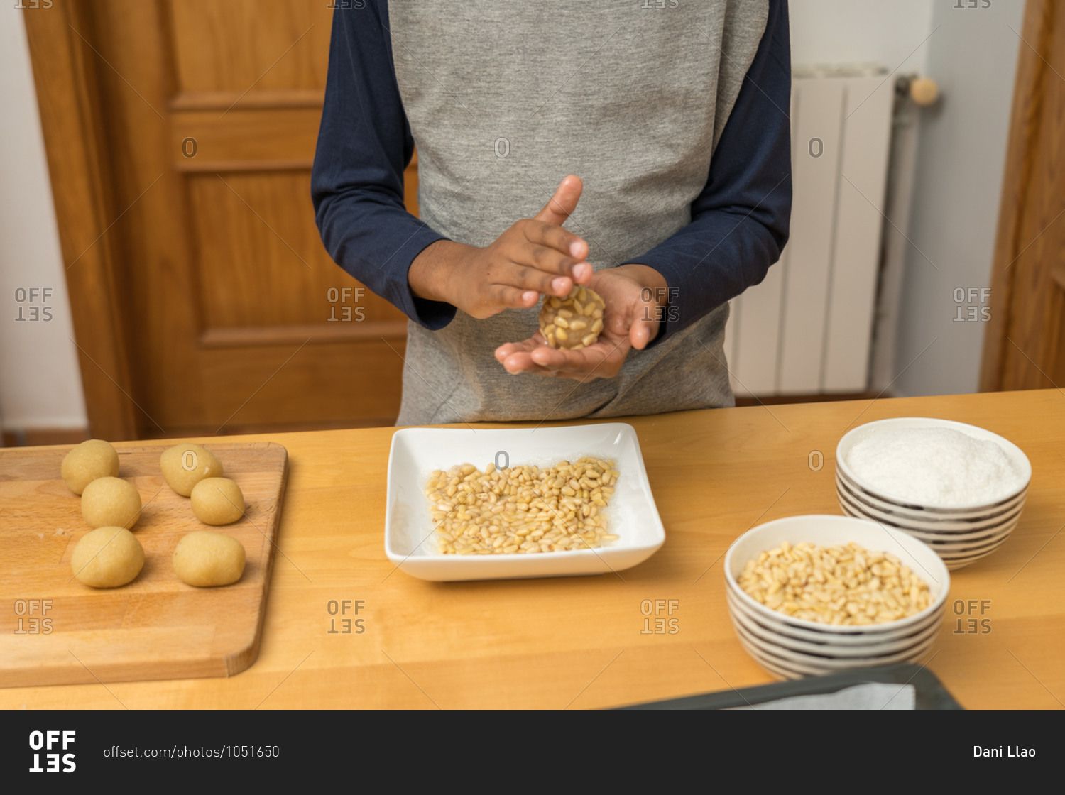 An unrecognizable African-American child shaping a round cookie made with ground almonds, grated coconut and pine nuts (panellets)