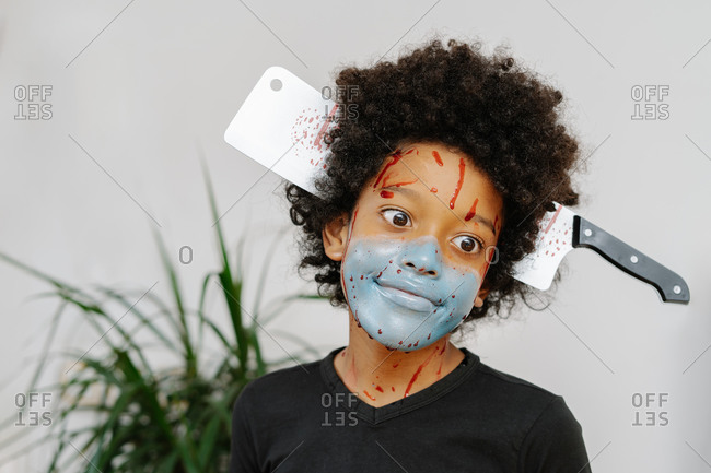 Portrait of afro boy with painted blue mask on his face. Halloween and carnival concept