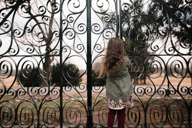 Young girl standing in front of a large iron gate
