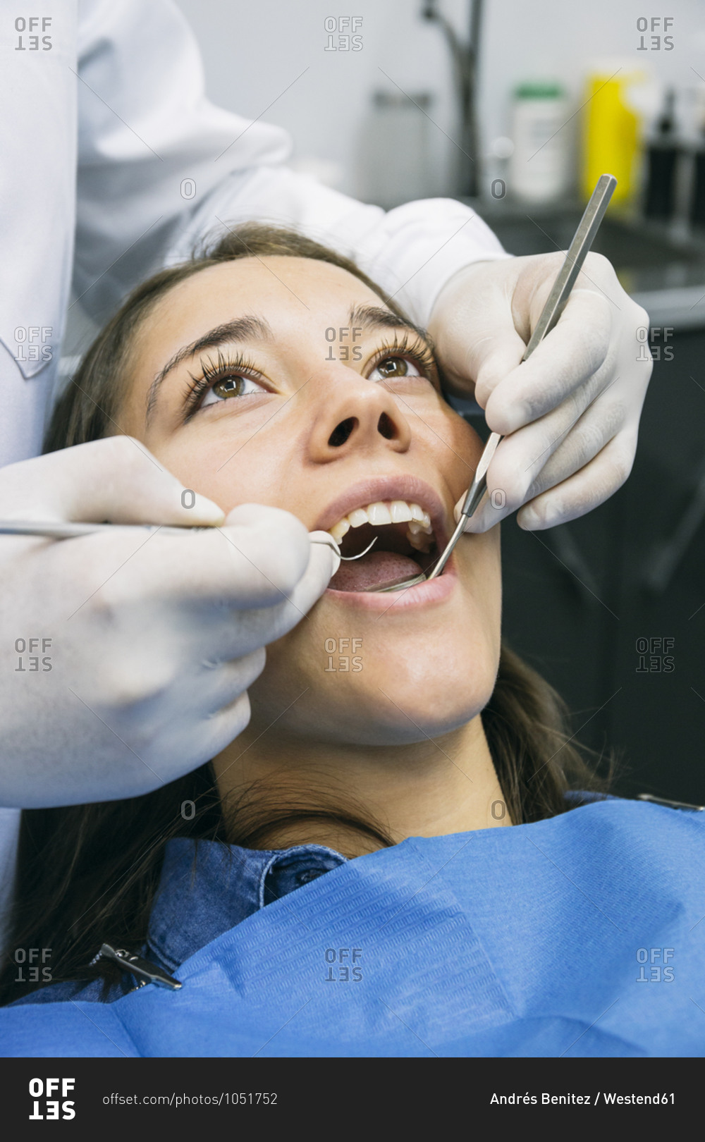 Dentist in gloves examining oral cavity of pretty patient at clinic