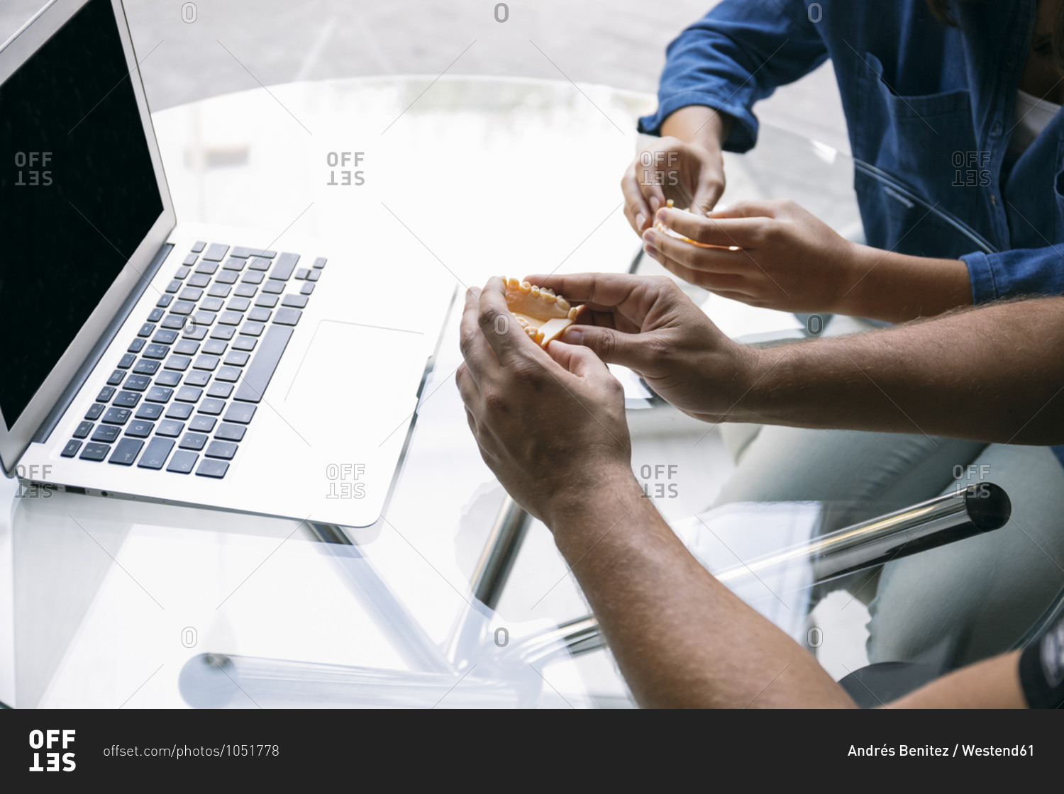 Male dentist discussing with female patient over gums model at desk in