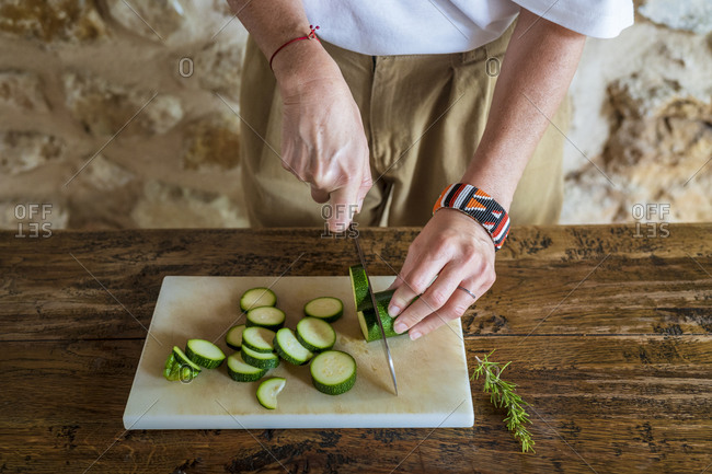Female dietitian cutting cucumber on marble board at table