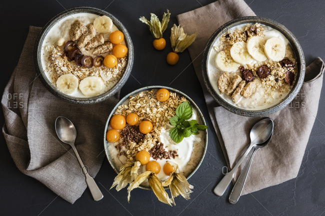 Three bowls of porridge with oats- flax seed- winter cherries and bananas
