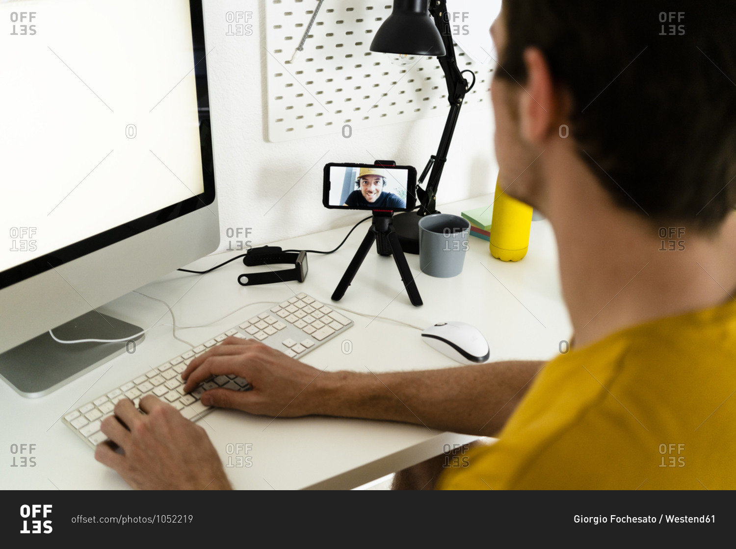Young man talking on video call while working on computer at home