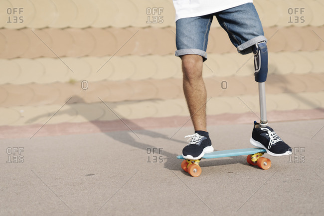 Young man with physical disability standing on skateboard at sports court