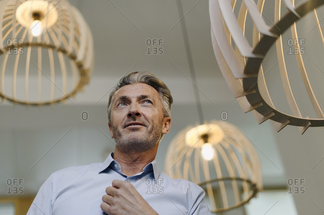 Businessman standing by illuminated light fixture at office