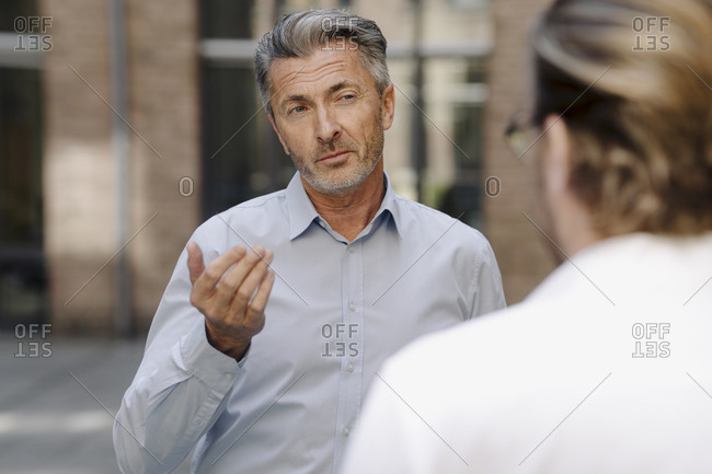 Businessman discussing with colleague while standing against building