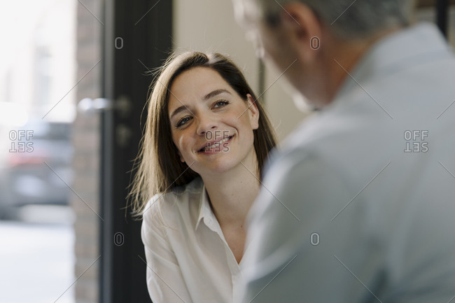 Smiling woman sitting by man at office
