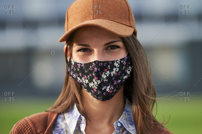 Young woman wearing cap and face mask standing in city
