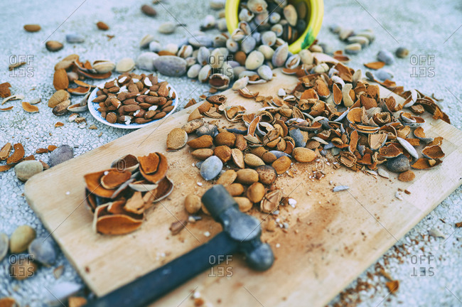 Peeled and whole almonds- empty husks- hammer and cutting board