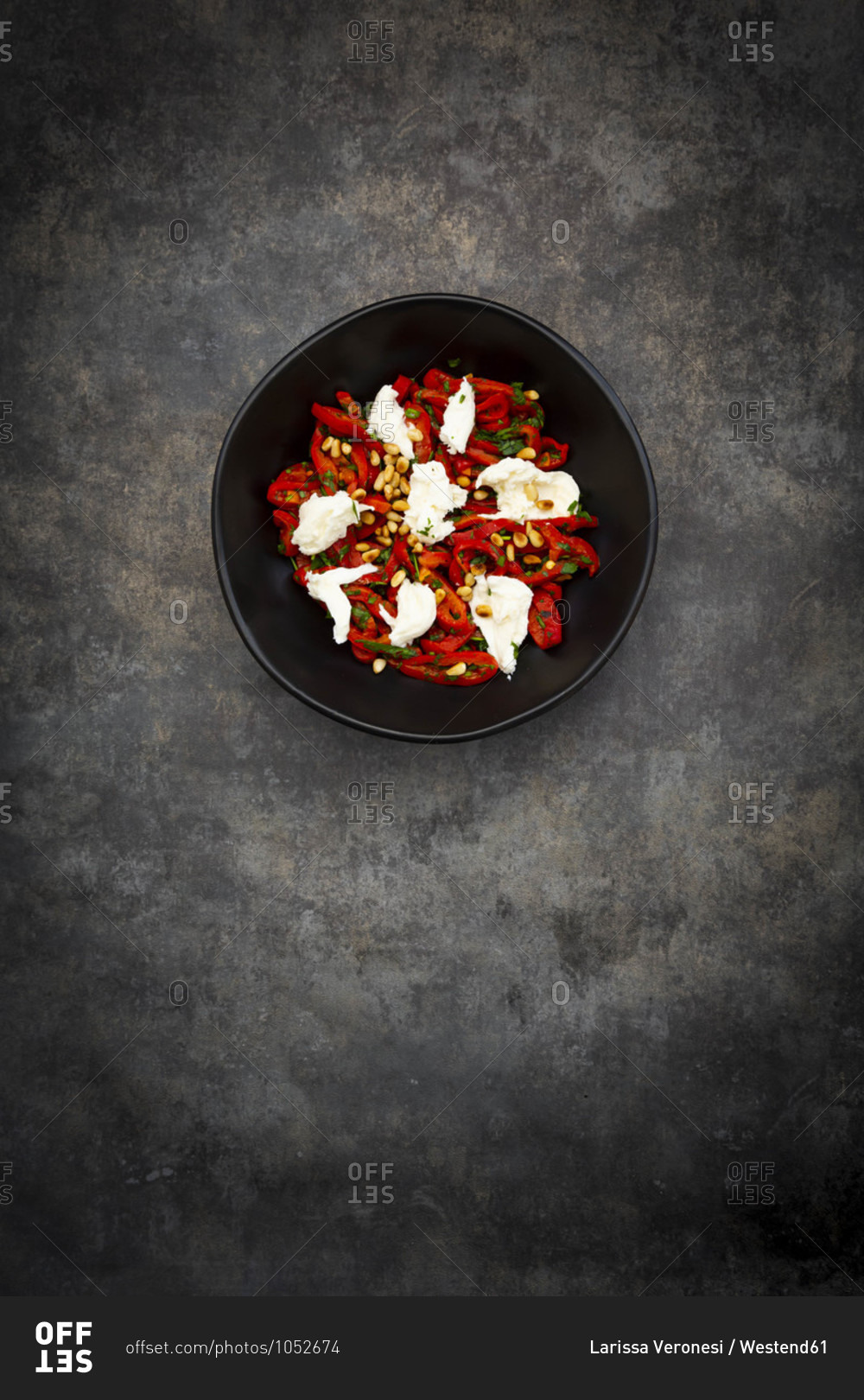 Bowl of vegetarian salad with red bell peppers- mozzarella- roasted pine nuts- parsley and chive