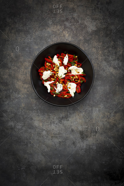 Bowl of vegetarian salad with red bell peppers- mozzarella- roasted pine nuts- parsley and chive