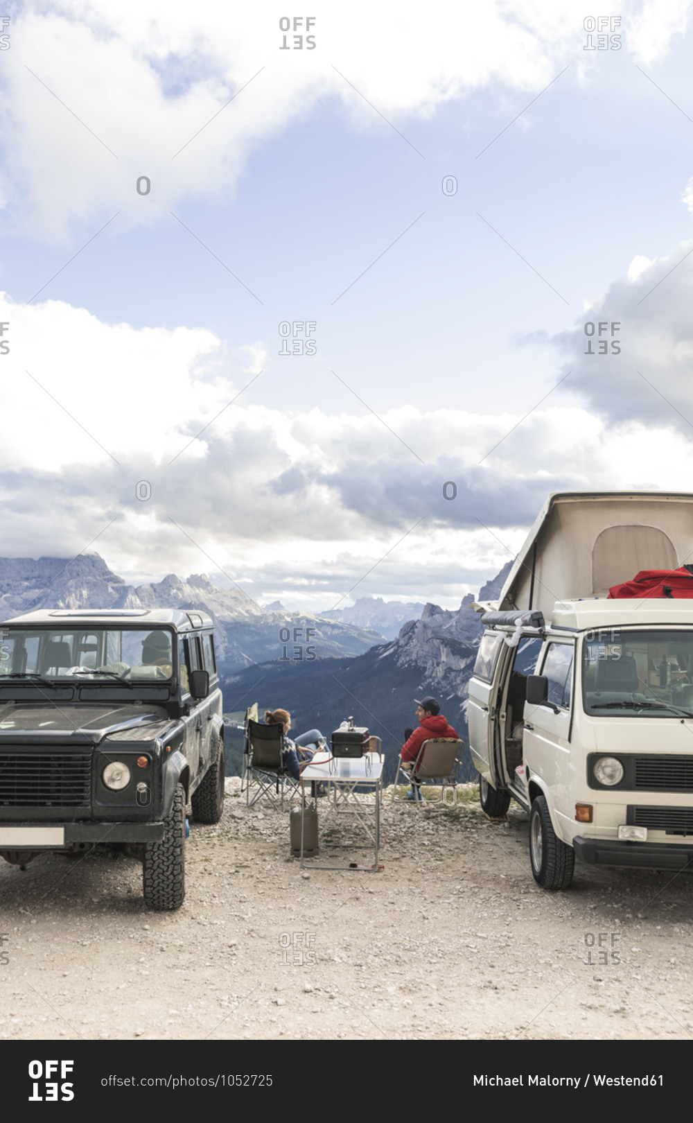 Male and female tourists enjoying vacation while sitting by vehicles at Sesto Dolomites- Dolomites- Alto Adige- Italy