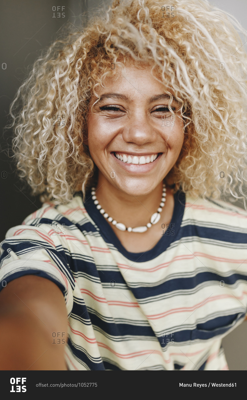 Happy Hispanic woman with blond curly hair taking selfie stock photo -  OFFSET
