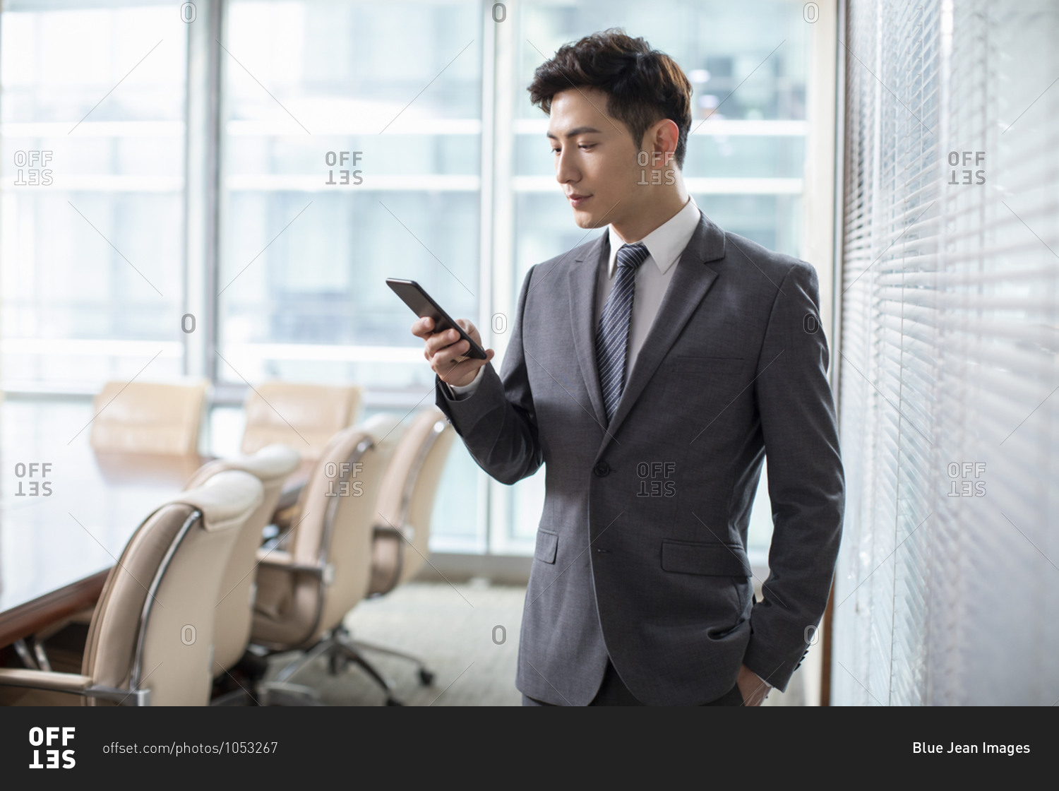 Confident Chinese businessman using smartphone in office