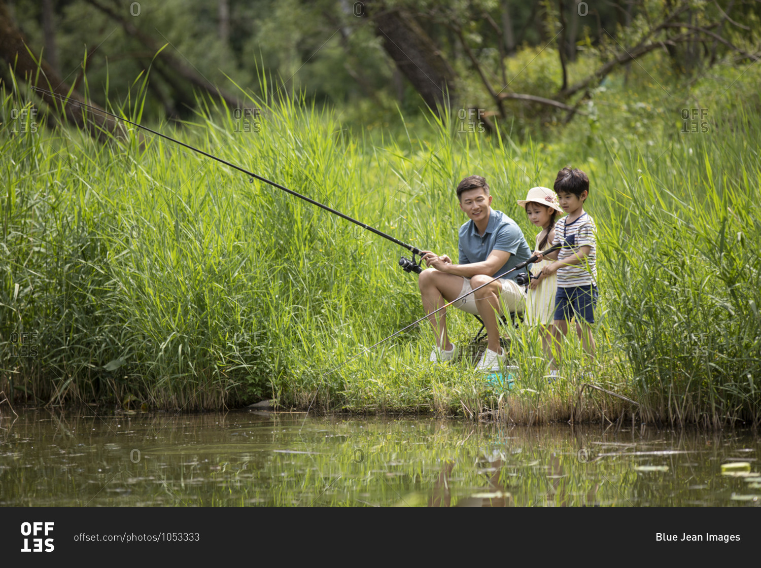Happy young Chinese family fishing by the river