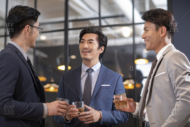 Successful Chinese businessmen drinking alcohol in office