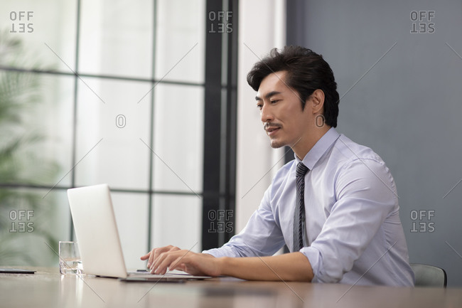 Successful Chinese businessman using laptop in office