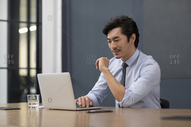 Successful Chinese businessman using laptop in office