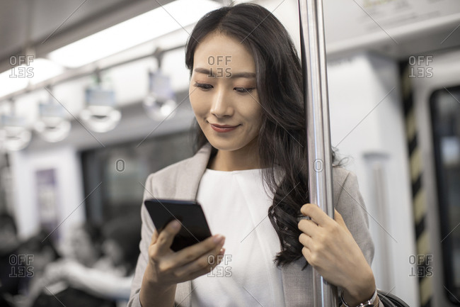 Young Chinese businesswoman using smartphone on subway