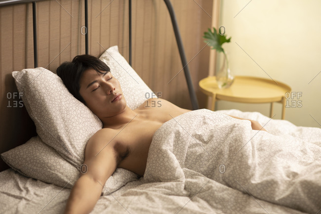 Young Chinese man sleeping in bed