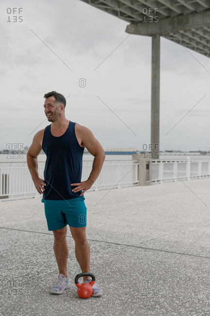 Middle-aged man working out with kettle bell under a bridge