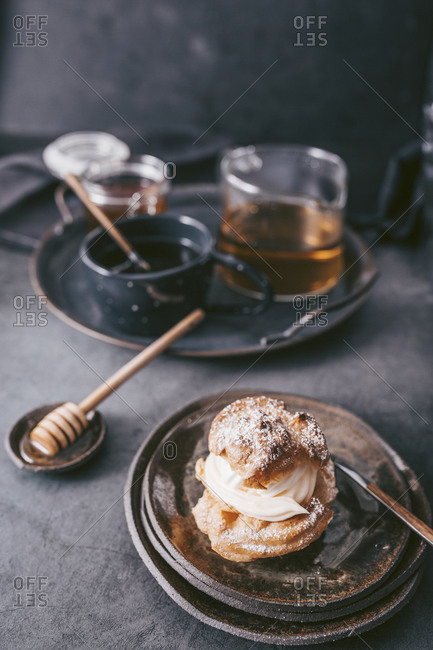 Cream filled pastry with cream filling served on rustic dish with tea in background
