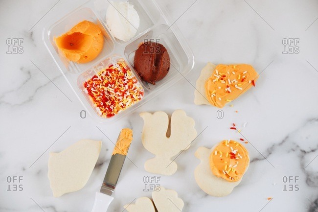 Thanksgiving sugar cookies being decorated on a white marble surface